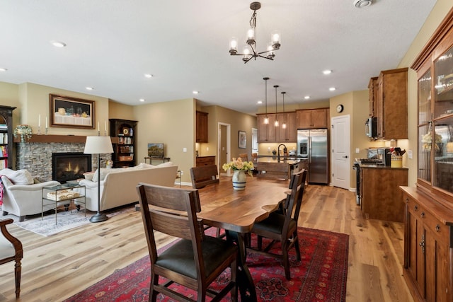 1101 Fabel Ln, Waconia, MN 55387 - dining space with light wood-style flooring, a chandelier, a stone fireplace, and recessed lighting