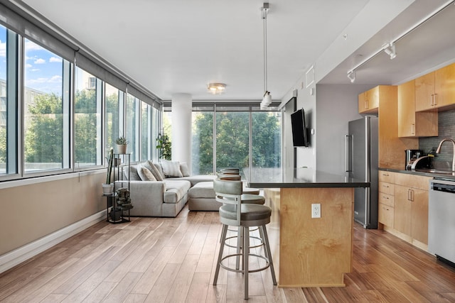8151 33rd Ave S Unit 201, Bloomington, MN 55425 - kitchen with light brown cabinets, appliances with stainless steel finishes, dark countertops, rail lighting, and a breakfast bar