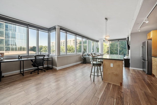 8151 33rd Ave S Unit 201, Bloomington, MN 55425 - kitchen with freestanding refrigerator, rail lighting, wood finished floors, a kitchen breakfast bar, and a kitchen island