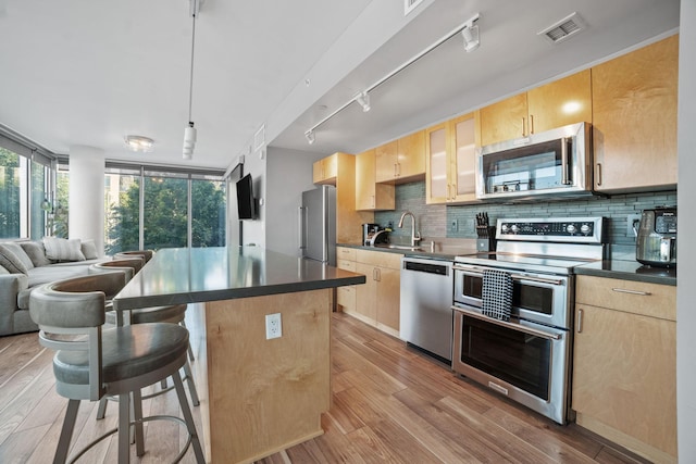 8151 33rd Ave S Unit 201, Bloomington, MN 55425 - kitchen featuring appliances with stainless steel finishes, light brown cabinetry, and backsplash