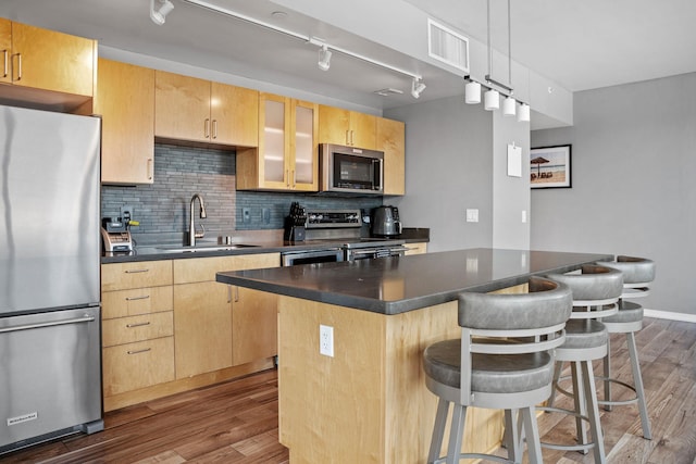 8151 33rd Ave S Unit 201, Bloomington, MN 55425 - kitchen with appliances with stainless steel finishes, light brown cabinetry, a breakfast bar area, dark countertops, and wood finished floors