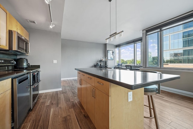 8151 33rd Ave S Unit 201, Bloomington, MN 55425 - kitchen with stainless steel appliances, a center island, dark wood finished floors, and dark countertops