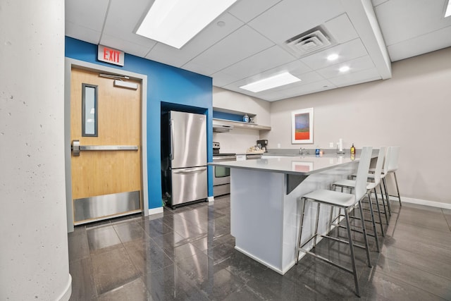 8151 33rd Ave S Unit 201, Bloomington, MN 55425 - kitchen featuring stainless steel appliances, a paneled ceiling, a kitchen bar, a peninsula, and open shelves