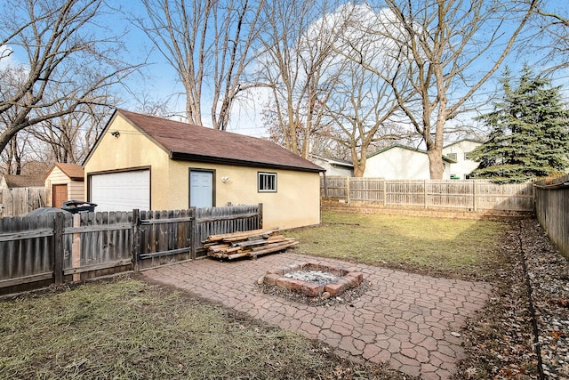 2074 Mcknight Rd N, North Saint Paul, MN 55109 - fenced backyard featuring an outdoor fire pit, an outbuilding, a detached garage, and a patio