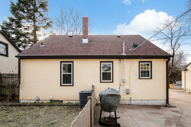 2074 Mcknight Rd N, North Saint Paul, MN 55109 - back of house featuring a shingled roof, a patio, stucco siding, and a chimney