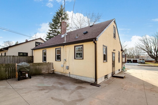 2074 Mcknight Rd N, North Saint Paul, MN 55109 - rear view of property featuring stucco siding, a patio area, a chimney, and roof with shingles