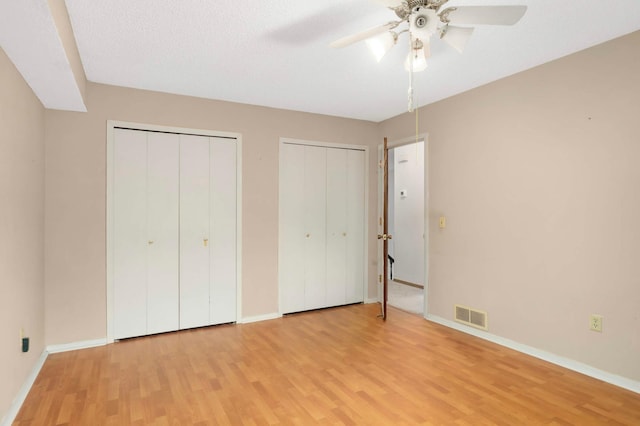 5698 Turtle Lake Rd, Shoreview, MN 55126 - unfurnished bedroom featuring two closets, light wood-style flooring, and a ceiling fan