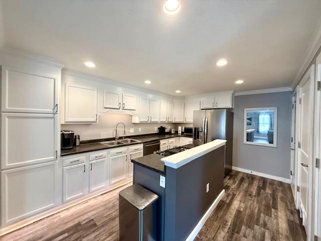 713 Grove St E, Caledonia, MN 55921 - kitchen featuring ornamental molding, white cabinets, dark countertops, a kitchen island, and dark wood-style flooring