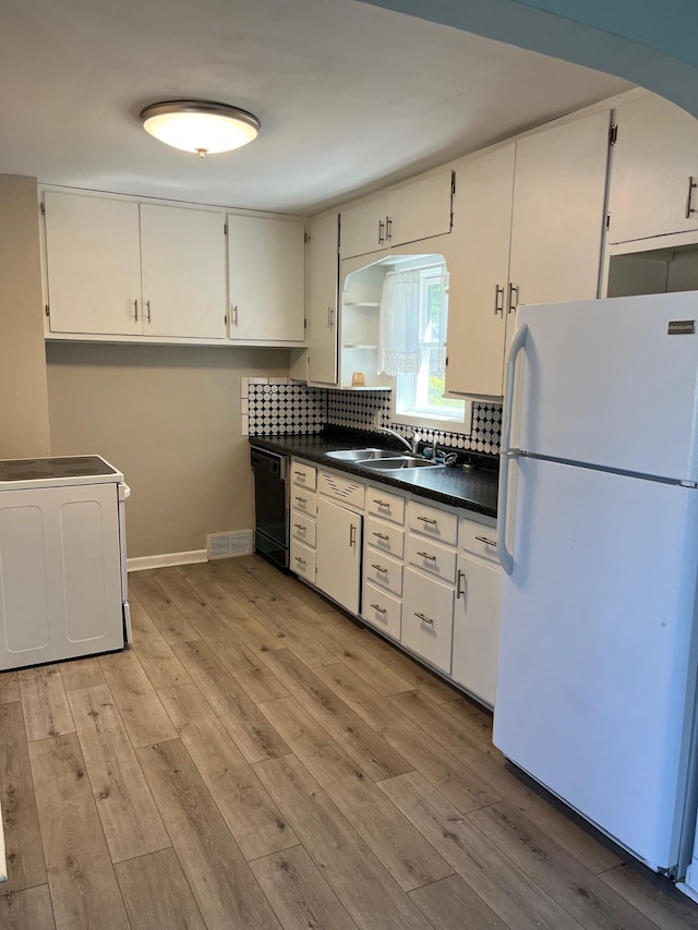 1017 Sibley Ave S, Litchfield, MN 55355 - kitchen with freestanding refrigerator, black dishwasher, dark countertops, light wood-style flooring, and decorative backsplash