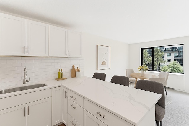 15 1st St Unit A307, Minneapolis, MN 55401 - kitchen with a peninsula, white cabinets, backsplash, a breakfast bar area, and light stone counters
