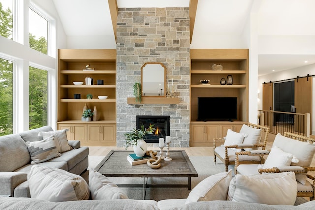 6176 Broadview Ave, Credit River Twp, MN 55372 - living room featuring a barn door, wood finished floors, high vaulted ceiling, a stone fireplace, and built in features