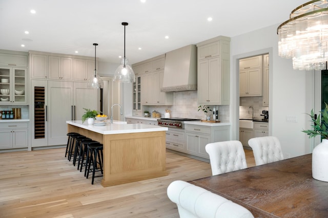 6176 Broadview Ave, Credit River Twp, MN 55372 - kitchen featuring premium range hood, stainless steel gas stovetop, tasteful backsplash, light wood-style floors, and a breakfast bar