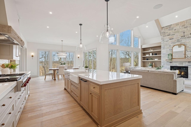 6176 Broadview Ave, Credit River Twp, MN 55372 - kitchen with premium range hood, stainless steel gas stovetop, light countertops, light wood-style flooring, and a stone fireplace