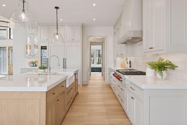 6176 Broadview Ave, Credit River Twp, MN 55372 - kitchen with premium range hood, stainless steel gas cooktop, decorative backsplash, light countertops, and light wood-style floors