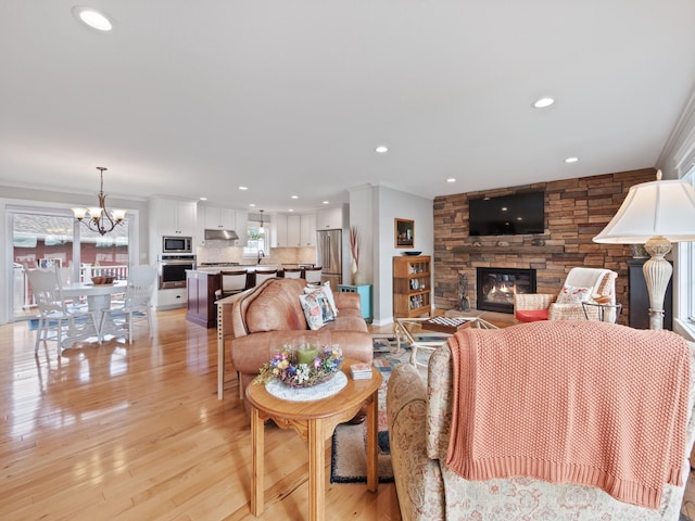 27842 Prairie Rose Rd, Elbow Lake, MN 56531 - living area with a stone fireplace, recessed lighting, a chandelier, light wood-style floors, and crown molding