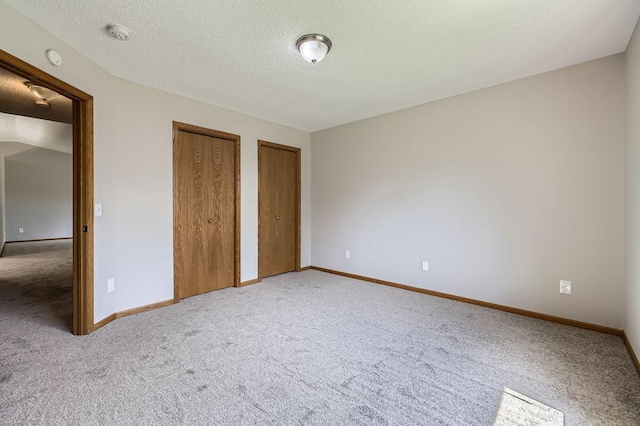 703 11th Ave SW, Isanti, MN 55040 - unfurnished bedroom featuring two closets, carpet flooring, and a textured ceiling