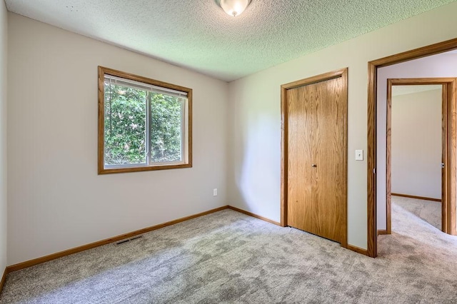 703 11th Ave SW, Isanti, MN 55040 - unfurnished bedroom featuring carpet floors, a textured ceiling, and a closet