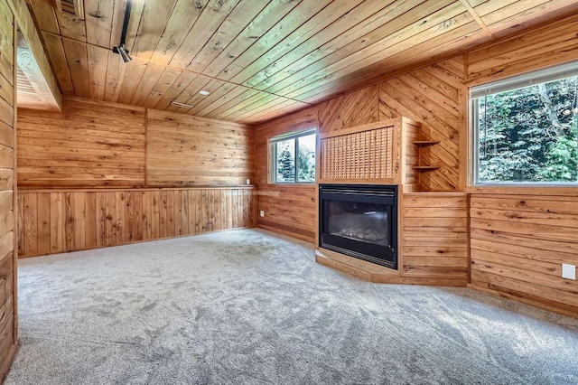 703 11th Ave SW, Isanti, MN 55040 - unfurnished living room with a glass covered fireplace, wood walls, wooden ceiling, and carpet flooring