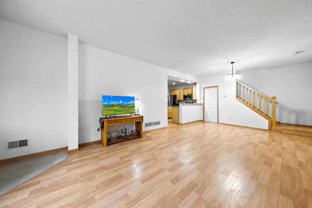 12240 Urbank St NE Unit G, Blaine, MN 55449 - unfurnished living room with light wood-style flooring, a chandelier, and stairs