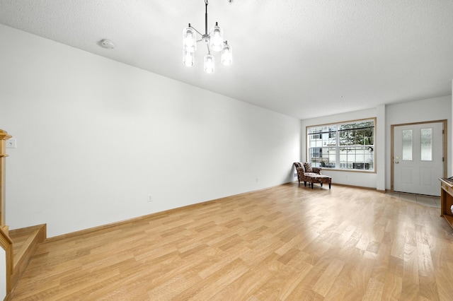 12240 Urbank St NE Unit G, Blaine, MN 55449 - unfurnished living room with light wood-style flooring, a chandelier, and a textured ceiling