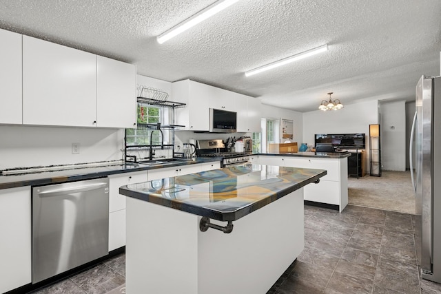 5070 10th St NW, Maple Lake, MN 55358 - kitchen with stainless steel appliances, dark countertops, a textured ceiling, a peninsula, and a center island