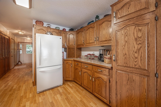 3925 Plainview Dr NW, Hackensack, MN 56452 - kitchen featuring freestanding refrigerator, brown cabinets, light wood-style floors, light countertops, and a textured ceiling