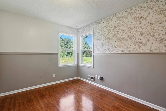 2314 347th Ave NE, Cambridge Twp, MN 55008 - unfurnished room with wood finished floors, wainscoting, a textured ceiling, and wallpapered walls