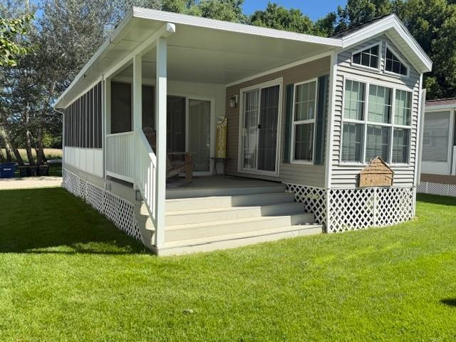 5055 Lake Mary Dr SW Unit 18, Alexandria, MN 56308 - rear view of house featuring a lawn and a sunroom