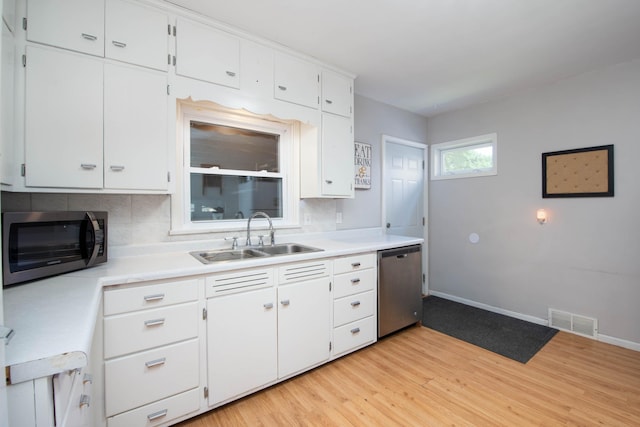 202 Silver St E, Mapleton, MN 56065 - kitchen with appliances with stainless steel finishes, light wood-type flooring, decorative backsplash, and light countertops