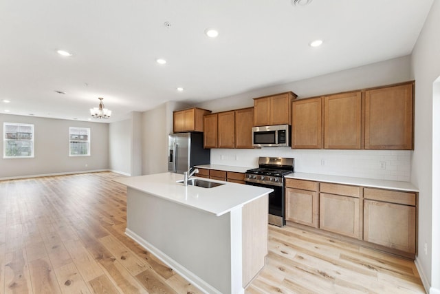 7443 E Ramsey Pkwy NW, Ramsey, MN 55303 - kitchen featuring stainless steel appliances, light wood-style floors, brown cabinets, a center island with sink, and backsplash