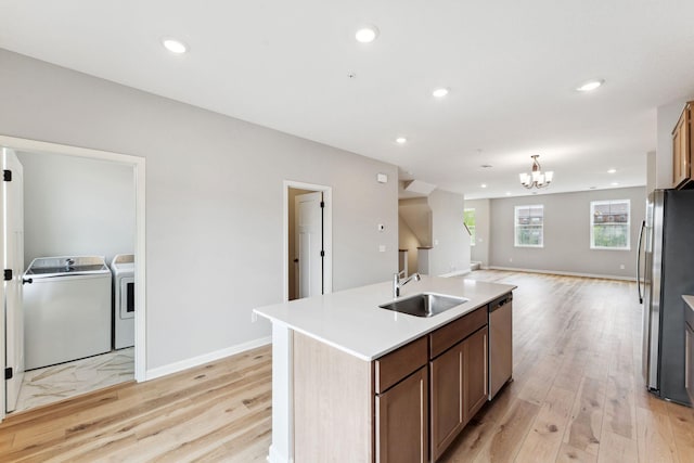 7443 E Ramsey Pkwy NW, Ramsey, MN 55303 - kitchen featuring appliances with stainless steel finishes, washing machine and clothes dryer, light wood-style floors, open floor plan, and an island with sink