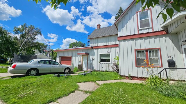 625 2nd Ave NE, Staples, MN 56479 - view of front facade featuring board and batten siding, a garage, a front lawn, and roof with shingles