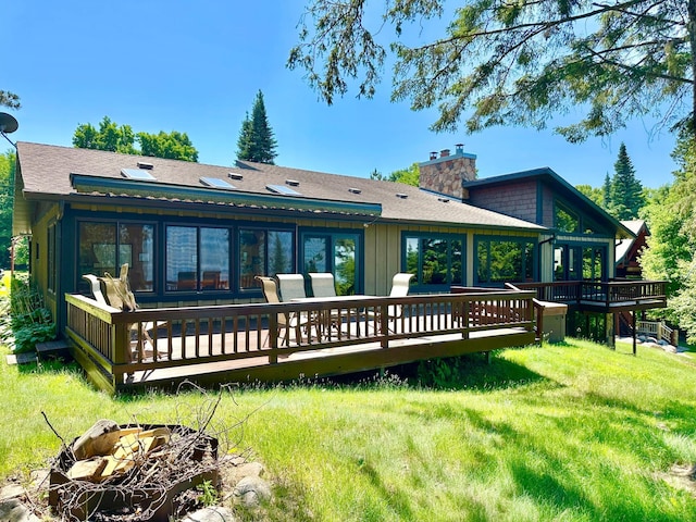 1938 Pine Cliff Rd NW, Walker, MN 56484 - back of property featuring a chimney, a wooden deck, a lawn, and a shingled roof