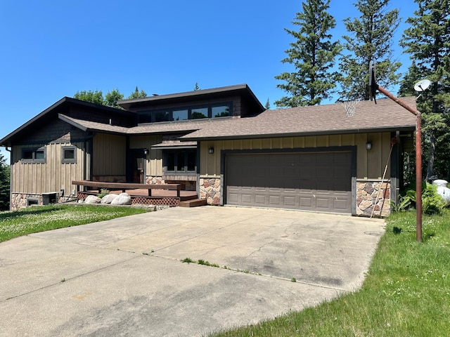 1938 Pine Cliff Rd NW, Walker, MN 56484 - view of front facade with stone siding, a garage, board and batten siding, roof with shingles, and driveway