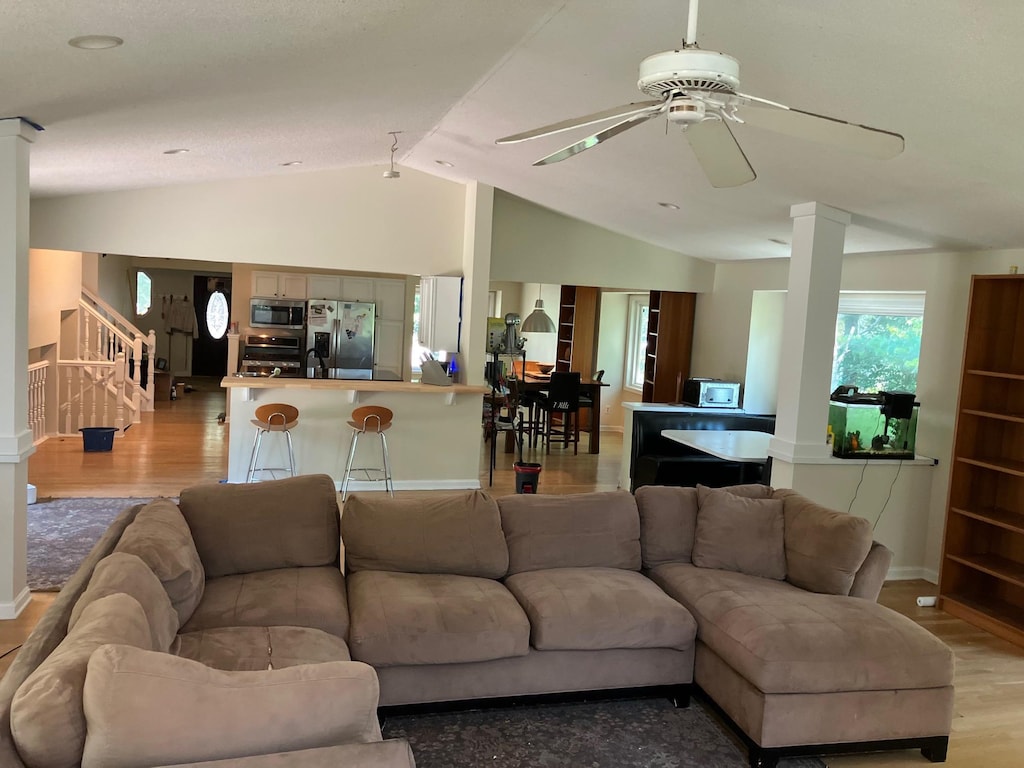14405 Drumlin Ct, Apple Valley, MN 55124 - living area with decorative columns, vaulted ceiling, stairs, light wood-style floors, and ceiling fan
