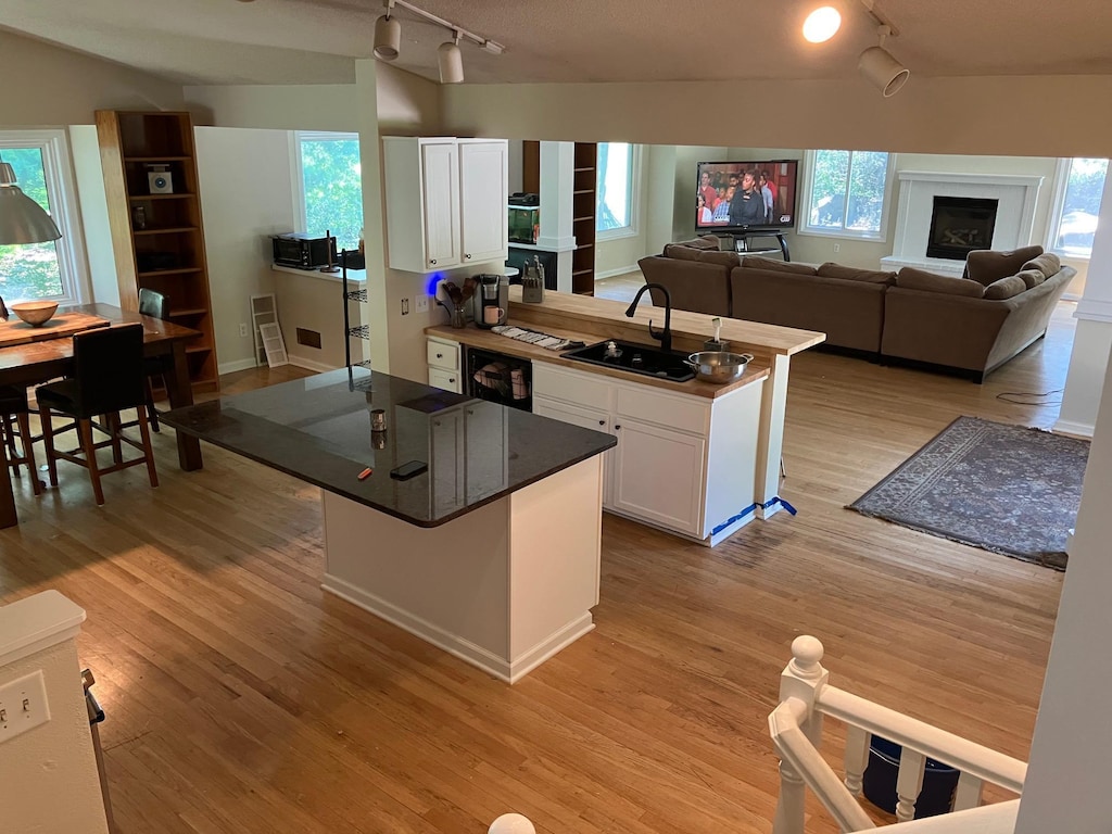 14405 Drumlin Ct, Apple Valley, MN 55124 - kitchen with rail lighting, white cabinetry, light wood-style flooring, and a peninsula