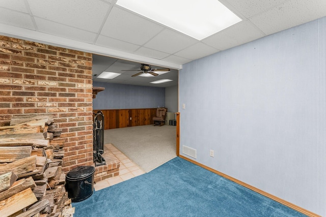 4885 262nd St, Wyoming, MN 55092 - below grade area with a drop ceiling, carpet, a wood stove, a ceiling fan, and wooden walls
