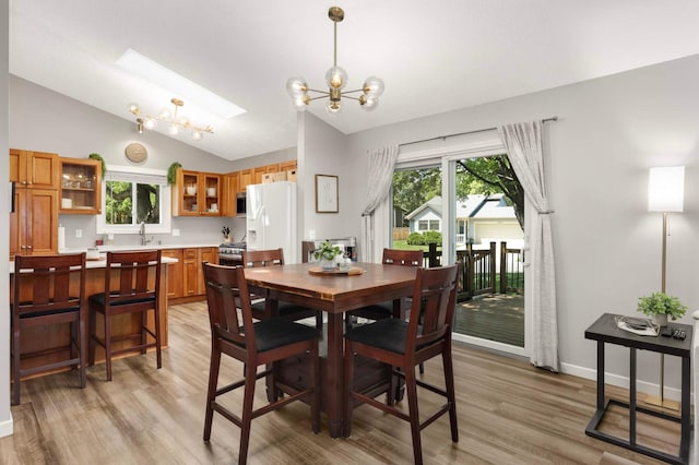 14301 Princeton Ave, Savage, MN 55378 - dining room featuring vaulted ceiling, a chandelier, light wood finished floors, and a skylight