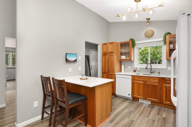 14301 Princeton Ave, Savage, MN 55378 - kitchen featuring light wood-style flooring, white appliances, brown cabinets, light countertops, and high vaulted ceiling