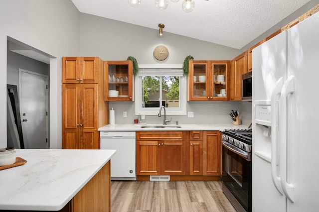 14301 Princeton Ave, Savage, MN 55378 - kitchen with stainless steel appliances, vaulted ceiling, brown cabinets, light wood finished floors, and glass insert cabinets