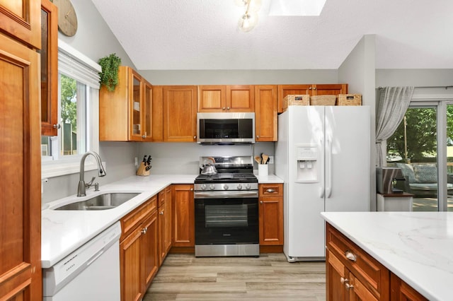 14301 Princeton Ave, Savage, MN 55378 - kitchen with appliances with stainless steel finishes, light wood finished floors, glass insert cabinets, brown cabinets, and a textured ceiling