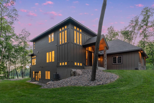 21386 Dorothy Way, Spring Lake Twp, MN 55372 - back of house at dusk with board and batten siding, a lawn, and a shingled roof