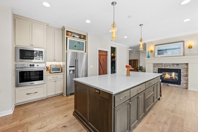 21386 Dorothy Way, Spring Lake Twp, MN 55372 - kitchen with stainless steel appliances, light wood-style flooring, a stone fireplace, light countertops, and hanging light fixtures