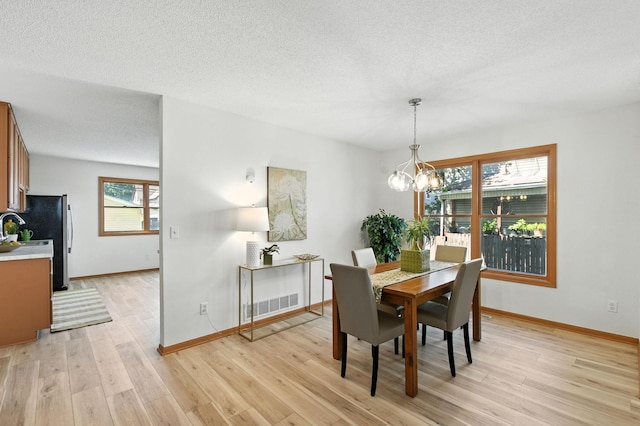 726 Thomas Ave, Saint Paul, MN 55104 - dining space with light wood-type flooring, a chandelier, and a textured ceiling