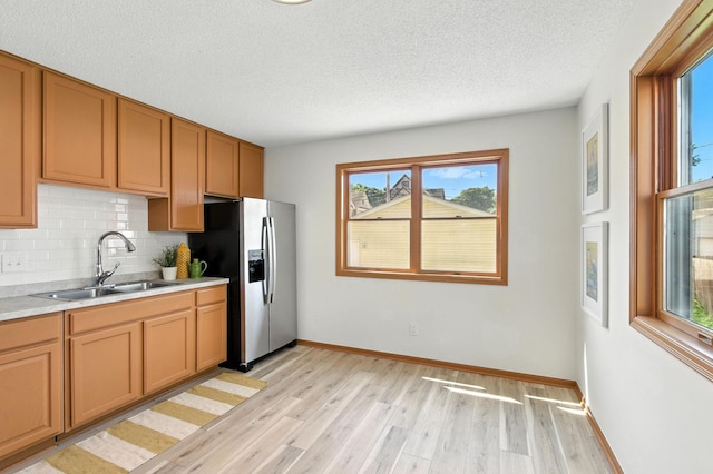 726 Thomas Ave, Saint Paul, MN 55104 - kitchen featuring stainless steel fridge with ice dispenser, light wood finished floors, a textured ceiling, backsplash, and light countertops