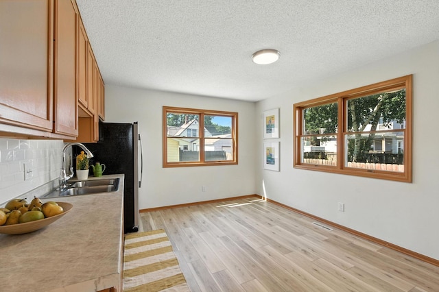 726 Thomas Ave, Saint Paul, MN 55104 - kitchen featuring a textured ceiling, light wood-type flooring, backsplash, light countertops, and brown cabinetry