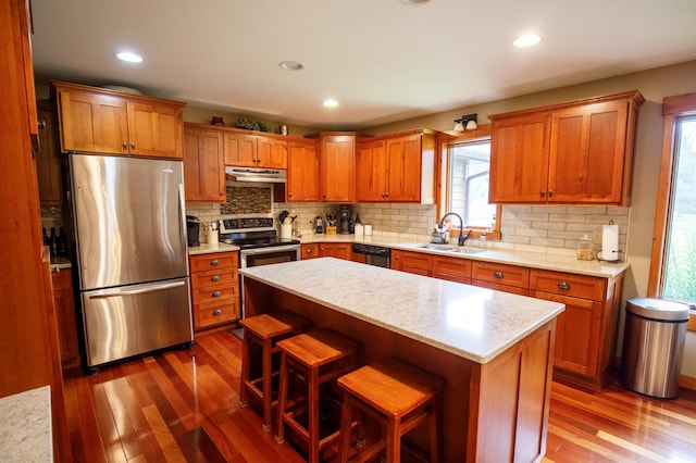 32433 Cedar St, Breezy Point, MN 56472 - kitchen featuring appliances with stainless steel finishes, under cabinet range hood, wood finished floors, brown cabinetry, and recessed lighting