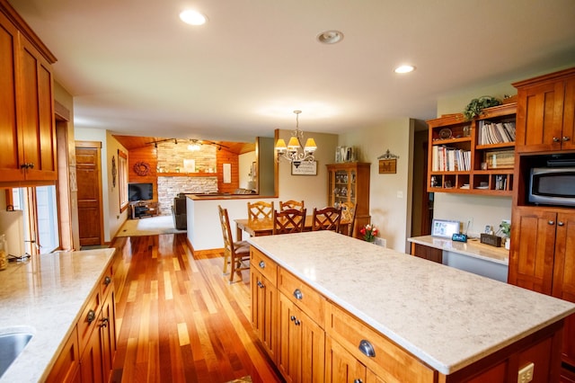 32433 Cedar St, Breezy Point, MN 56472 - kitchen with light wood finished floors, stainless steel microwave, a chandelier, a fireplace, and open floor plan