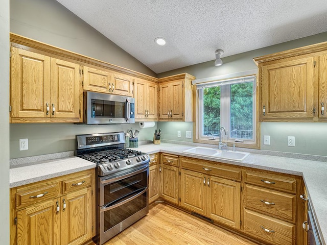 1483 Woods Creek Dr, Delano, MN 55328 - kitchen featuring appliances with stainless steel finishes, a textured ceiling, light countertops, vaulted ceiling, and light wood finished floors