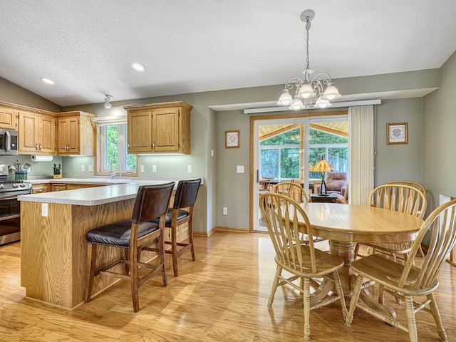 1483 Woods Creek Dr, Delano, MN 55328 - kitchen featuring appliances with stainless steel finishes, a textured ceiling, light countertops, light wood finished floors, and a chandelier
